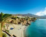 Sonnige playa de calahonda mit Palmen, weißem Sand, türkisfarbenem Meer und Bergen im Hintergrund.