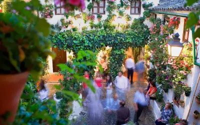 Blühende patios in Córdoba, mit Menschen, die durch den üppig begrünten Innenhof schlendern.