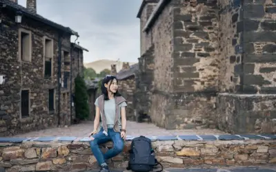 Junge Frau sitzt auf Steinmauer in historischem Dorf in Guadalajara, Spanien.