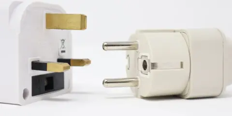 Reiseadapter für den Strom in Spanien. Ein britischer Stecker trifft auf einen europäischen Stecker.