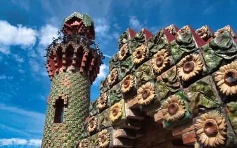 Bunte Sonnenblumen zieren die Fassade eines Turms in Comillas, Spanien.