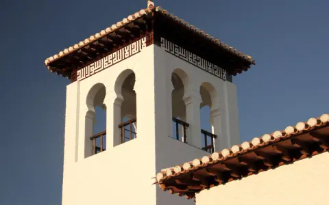 Weiße Moschee in Granada mit arabischer Kalligrafie und maurischen Bögen.