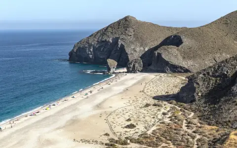 Sonnige Playa de los Muertos mit türkisfarbenem Meer, Felsen und vielen Sonnenanbetern.