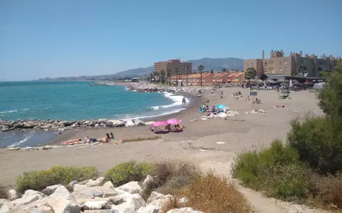 Sonniger Tag am playa de guadalmar mit Menschen, die sich am Strand sonnen und im türkisfarbenen Meer schwimmen.