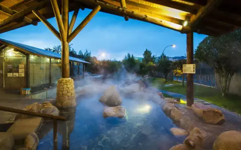 Dampfender Thermalpool unter einem Holzpavillon in Ourense, Spanien. Entspannung pur in der Abenddämmerung.