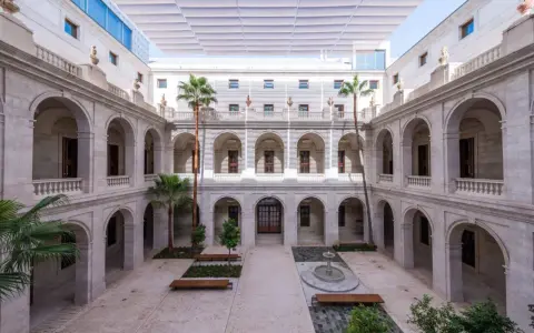 Hof des Malaga Museums mit Arkaden, Palmen und einem Brunnen.