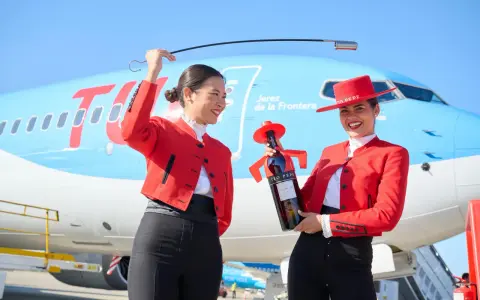 Zwei Frauen in Flamenco-Kleidung am Flughafen Jerez. Eine hält eine Flasche Tio Pepe Sherry, die andere eine Peitsche.