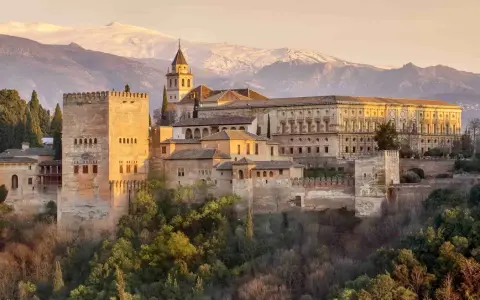 Die Alhambra in Granada, ein Traumziel nach einer Reise von Sevilla. Majestätische Festungsmauern und Paläste vor schneebedeckten Bergen.