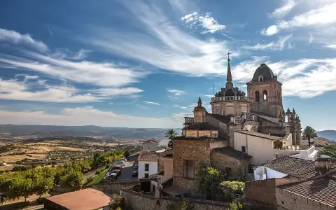 Blick auf die historische Stadt Jerez de los Caballeros mit ihren beeindruckenden Kirchtürmen unter einem dramatischen Himmel.
