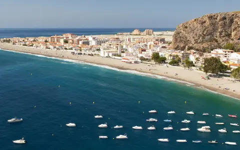 Traumhafte Küstenlandschaft an der Costa Tropical mit weißem Sandstrand, türkisfarbenem Meer und vielen kleinen Booten.