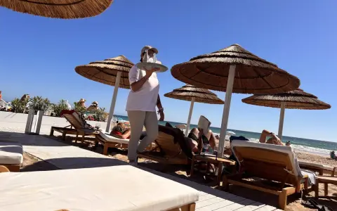Kellnerin bringt Getränke an Liegestühle am Strand. Perfekte Feiertage Spanien!