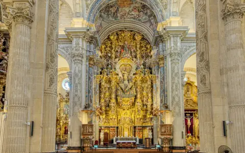 Prunkvoller Altar im Kathedrale Sevilla Innenraum, verziert mit goldenen Skulpturen und Malereien, die eine himmlische Szene darstellen.